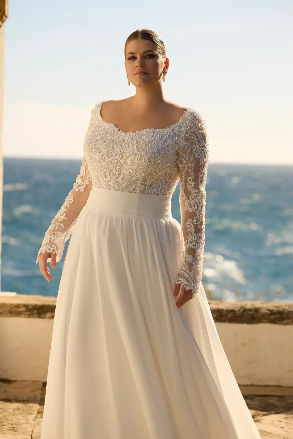 model is wearing a long sleeve lace bridal gown